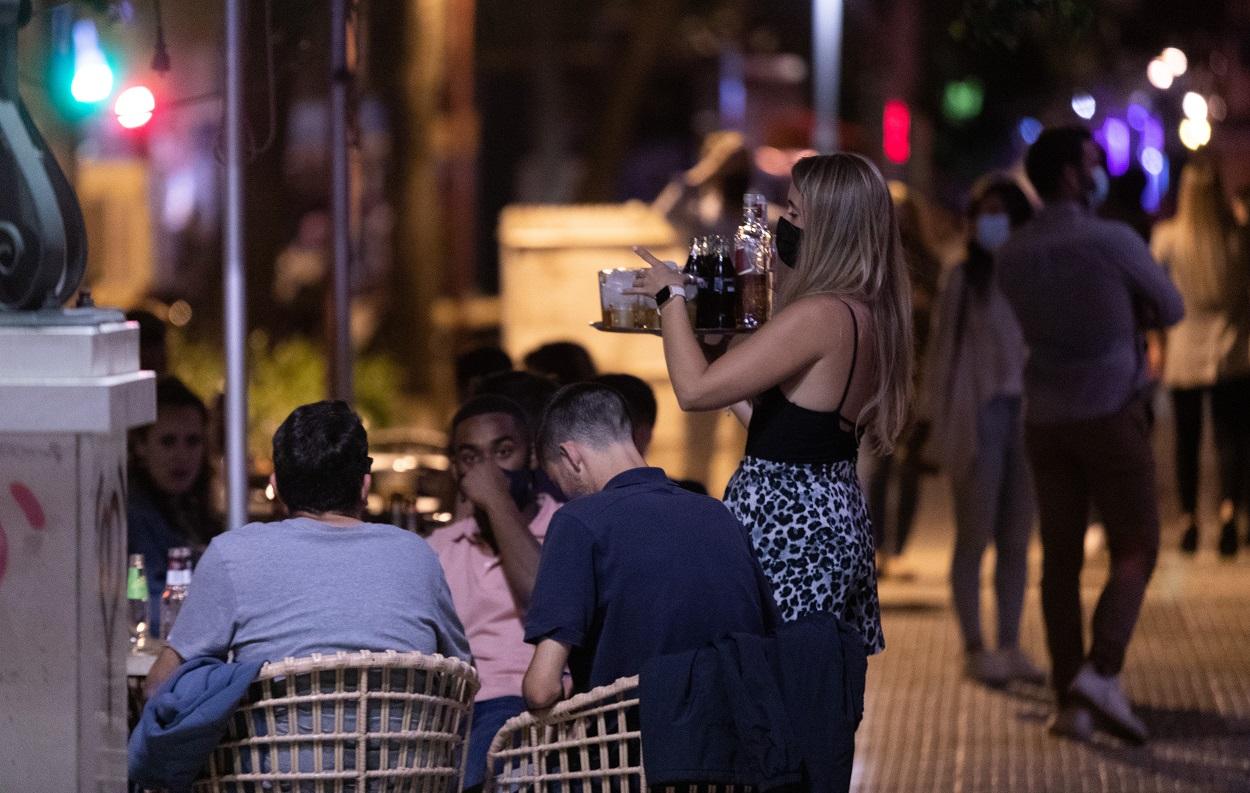 Una camarera atiende a varias personas en la terraza de un bar de Sevilla. Fuente: Europa Press.