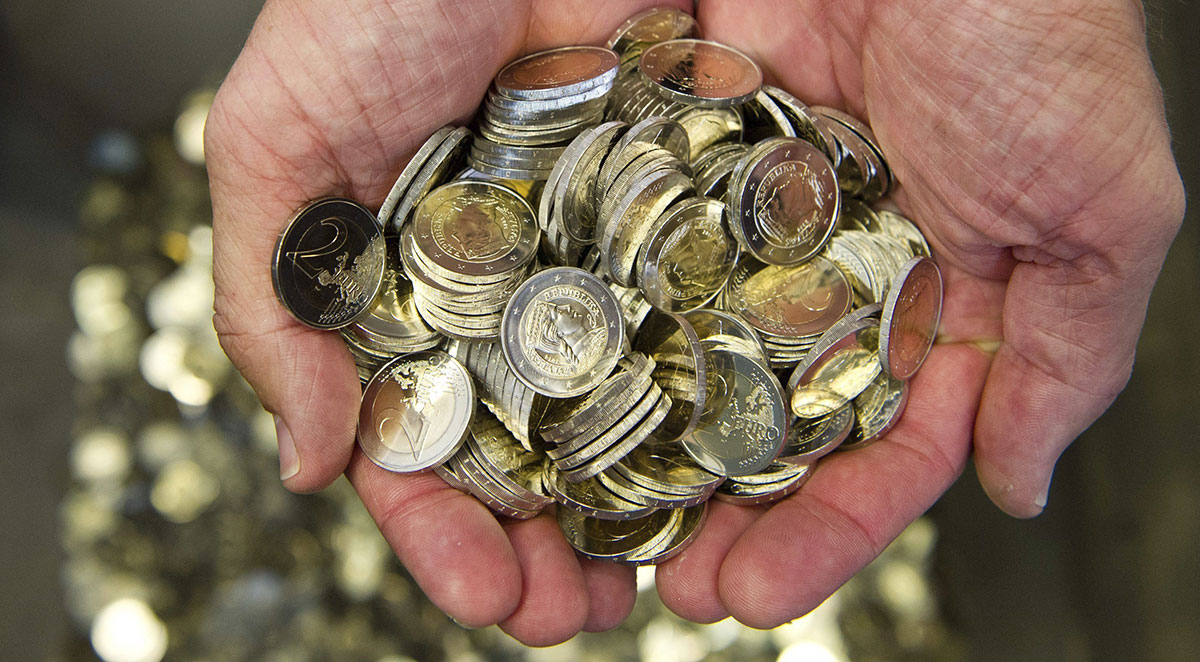 Un hombre sostiene varias monedas de euros 