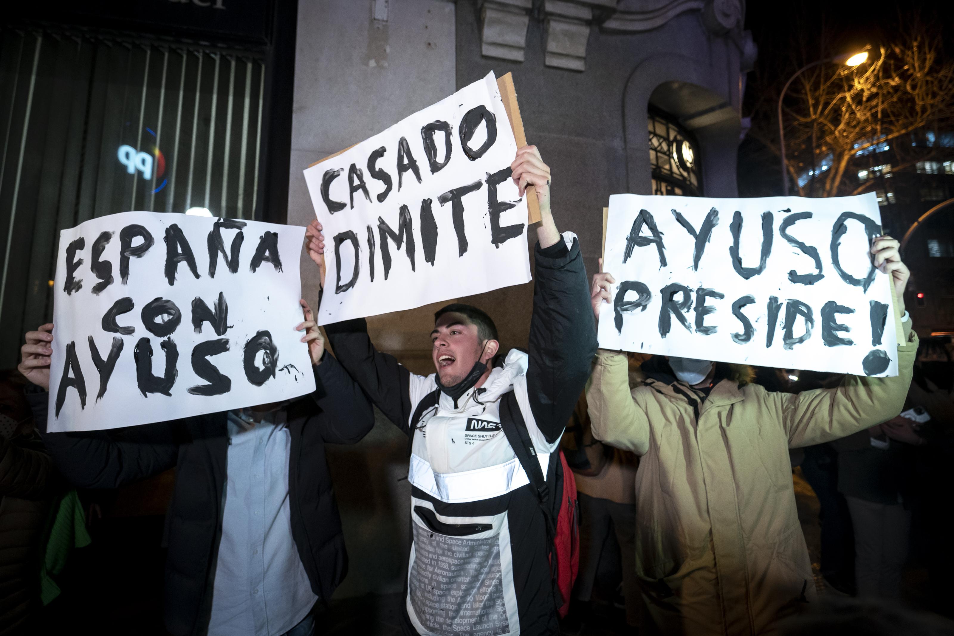 Varias personas sostienen pancartas durante una manifestación en apoyo a la presidenta de la Comunidad de Madrid, Isabel Díaz Ayuso, frente de la sede del Partido Popular en la calle Génova.
