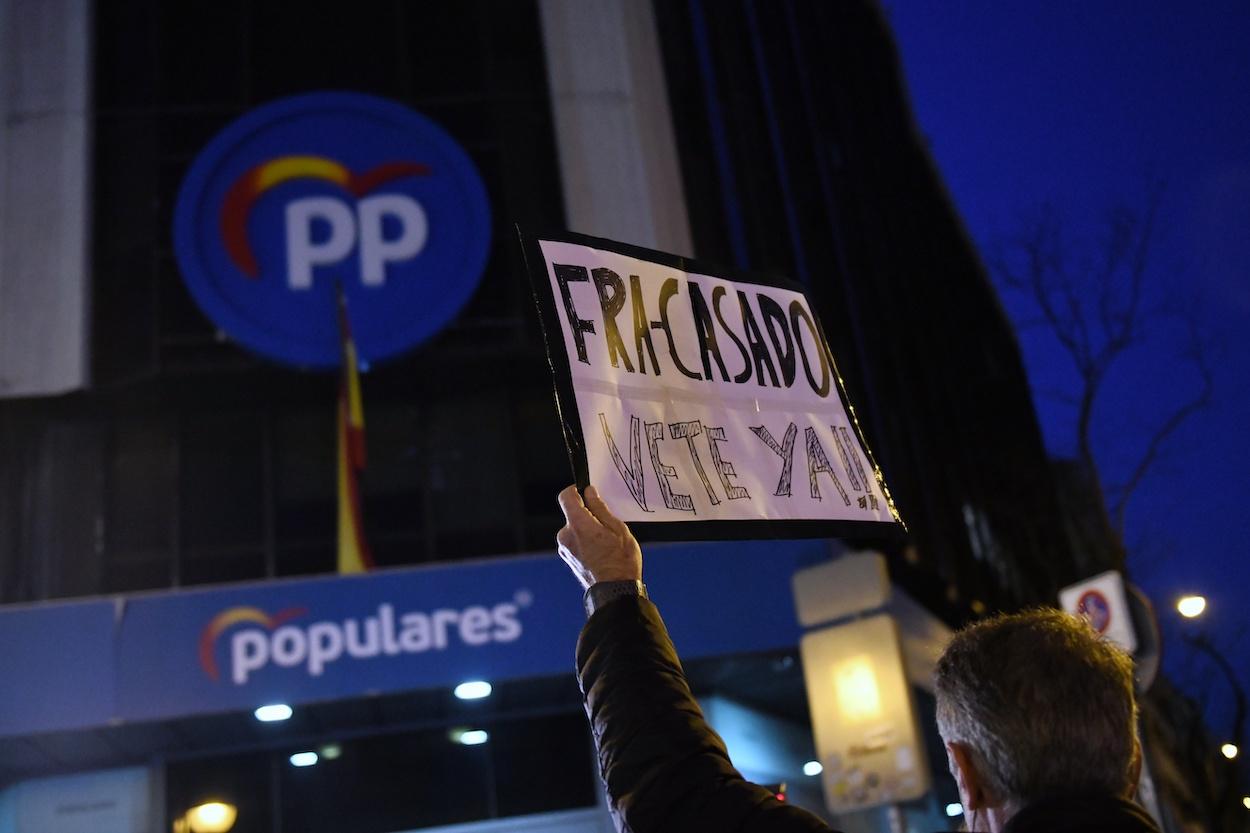 Un hombre sostiene un cartel en referencia a Pablo Casado, durante una manifestación en apoyo a la presidenta de la Comunidad de Madrid, Isabel Díaz Ayuso, frente de la sede del Partido Popular en la calle Génova