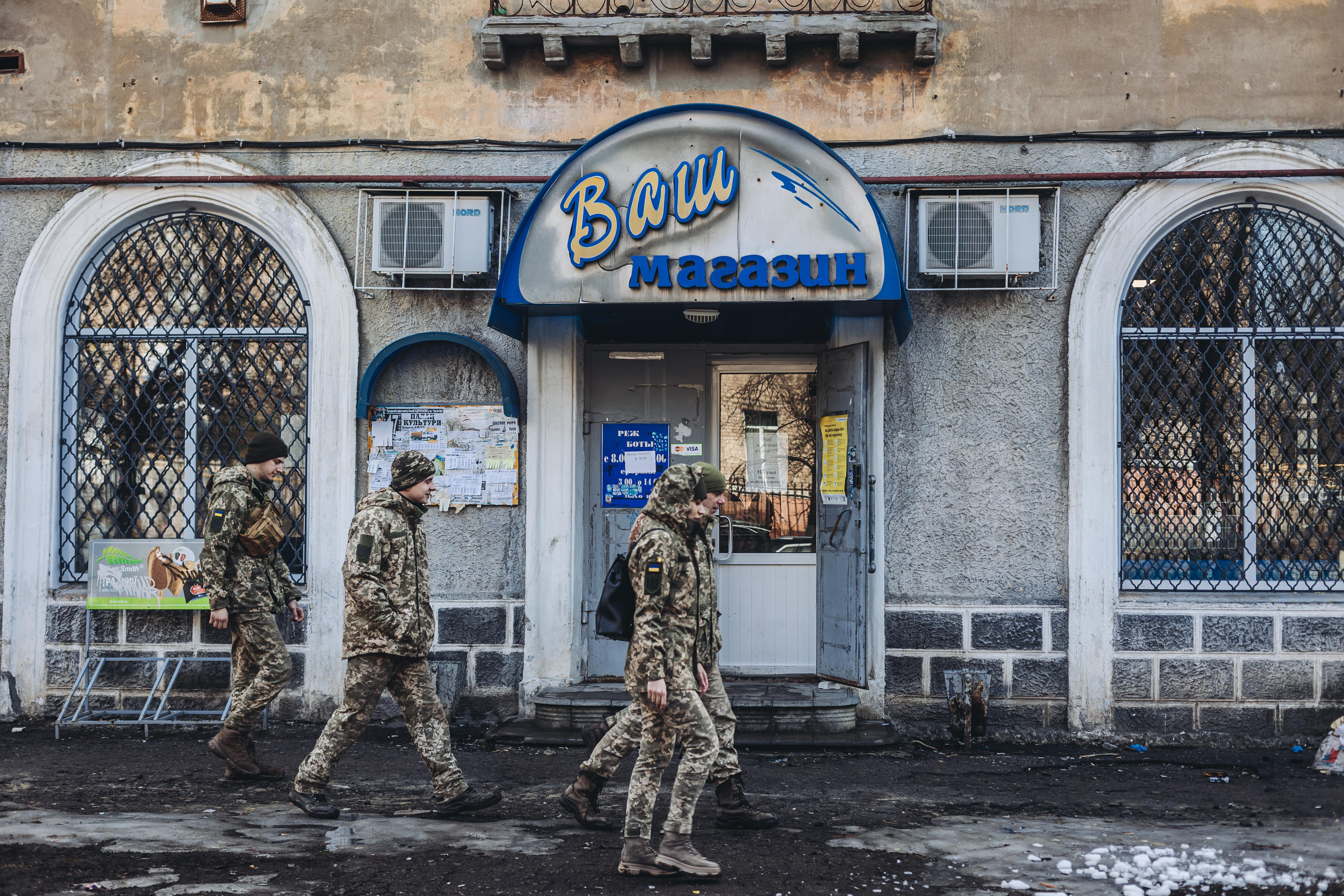Unos soldados caminan delante de una tienda local, a 23 de febrero de 2022, en Chasiv Yar, Oblast de Donetsk (Ucrania). Diego Herrera / Europa Press