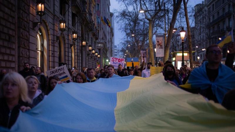Un grupo de personas sostienen la bandera de Ucrania en una concentración ante la embajada rusa en Barcelona.