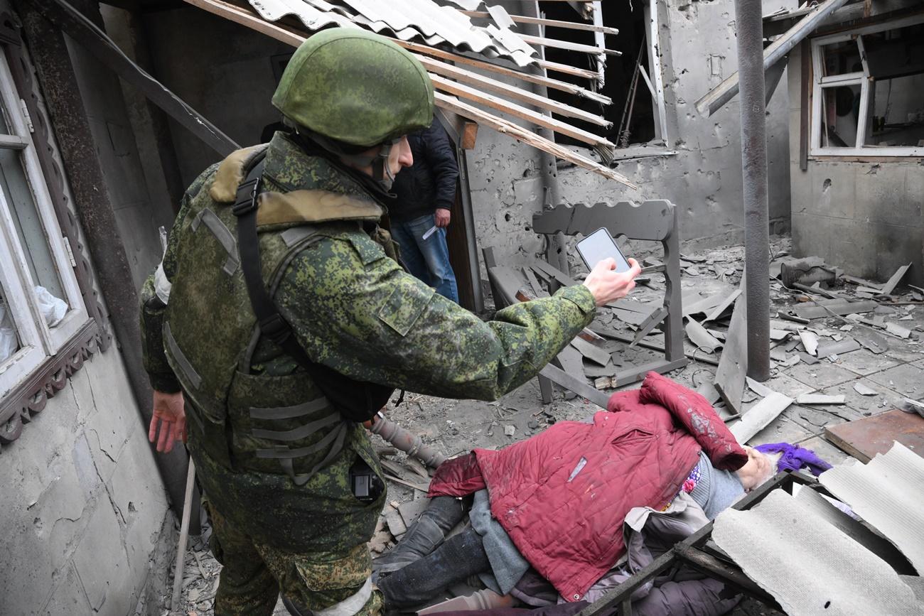 Un empleado de la Milicia Popular de la RPD toma una foto de una mujer asesinada en el patio de una casa, en Donetsk