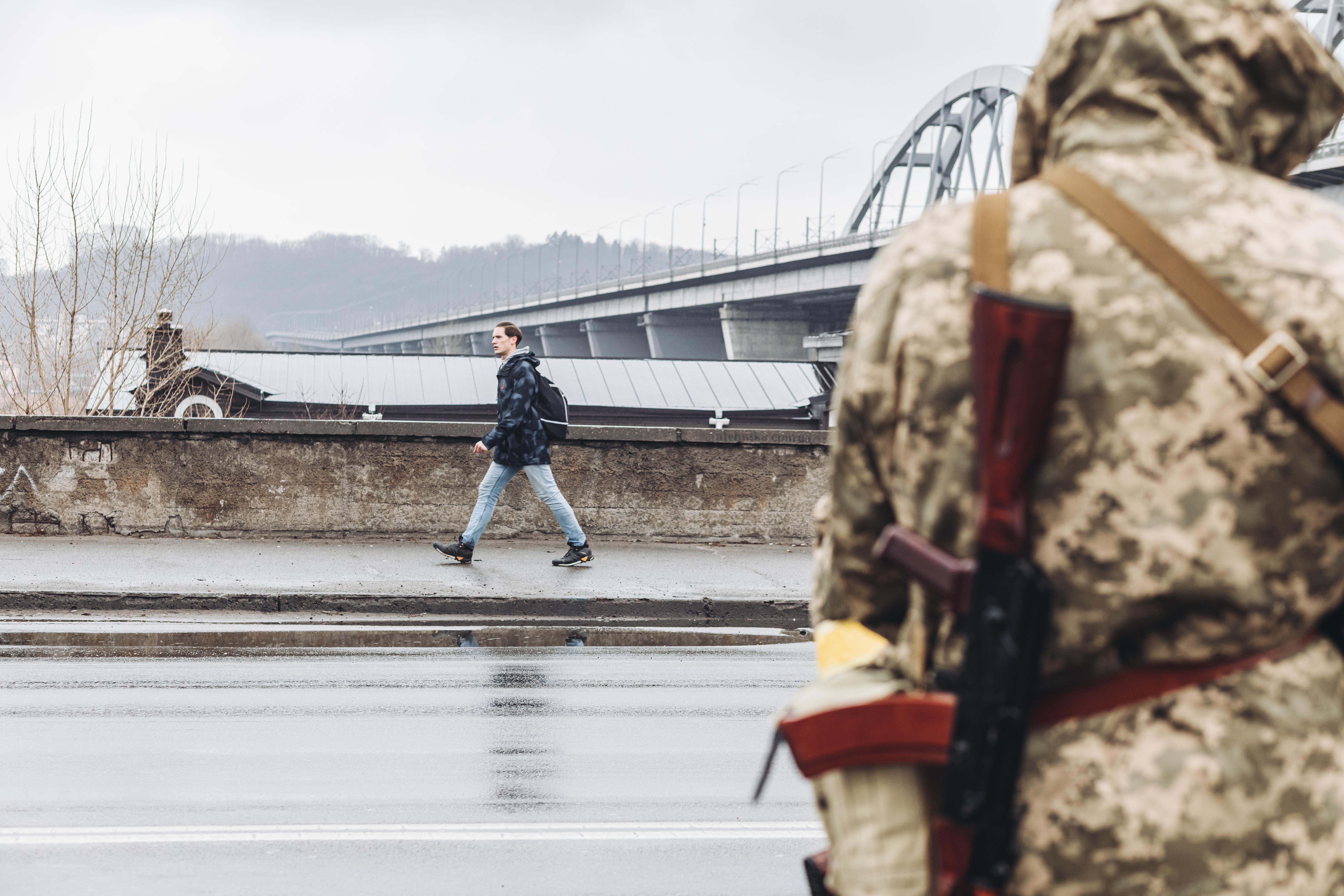 Un civil camina frente a un miliciano ucraniano por una calle de Kiev. Diego Herrera / Europa Press