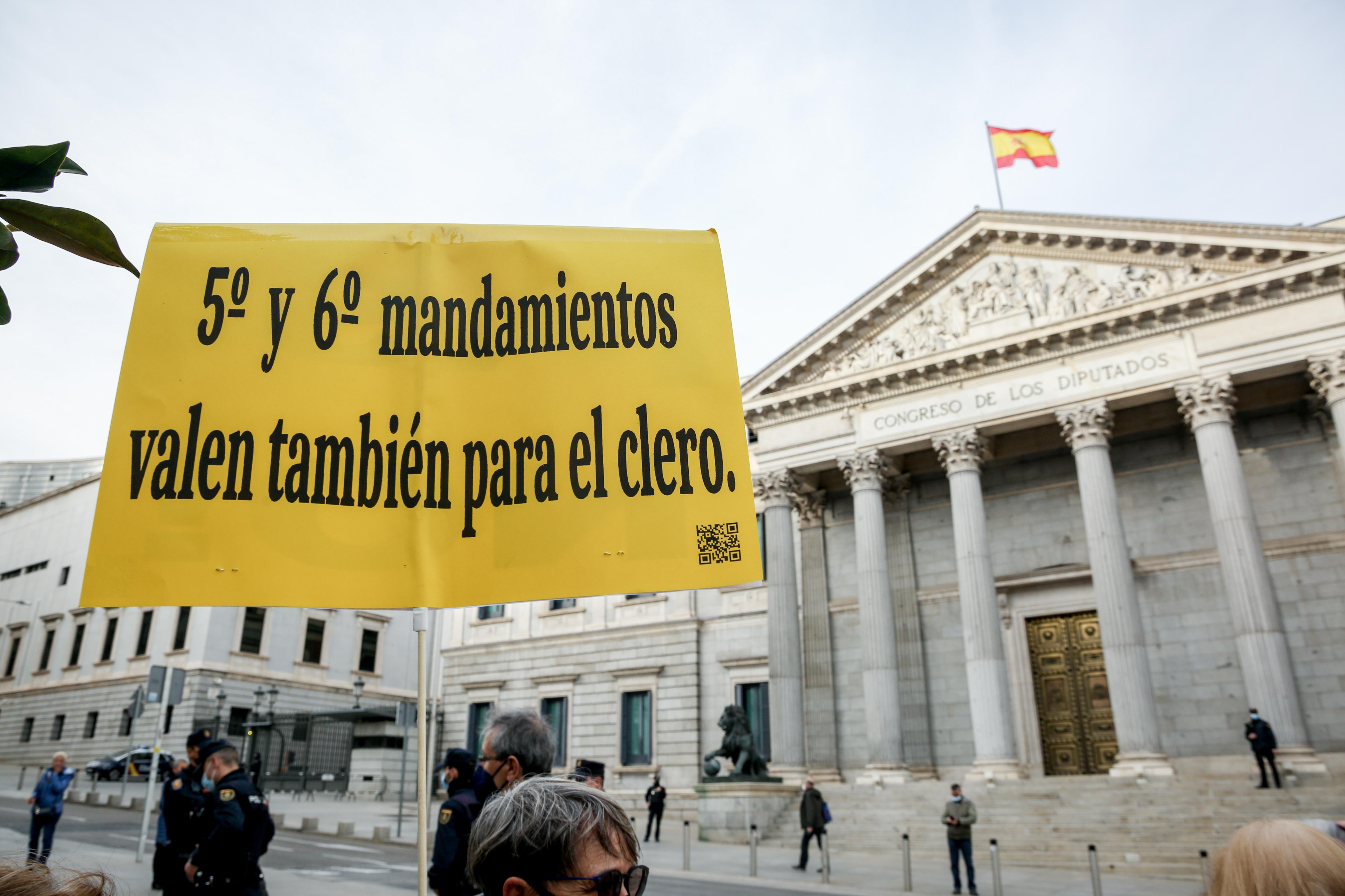 Una mujer con un cartel en el que se lee: '5º y 6º mandamiento también para el clero', participa en una concentración a las puertas del Congreso de los Diputados. Ricardo Rubio / Europa Press.