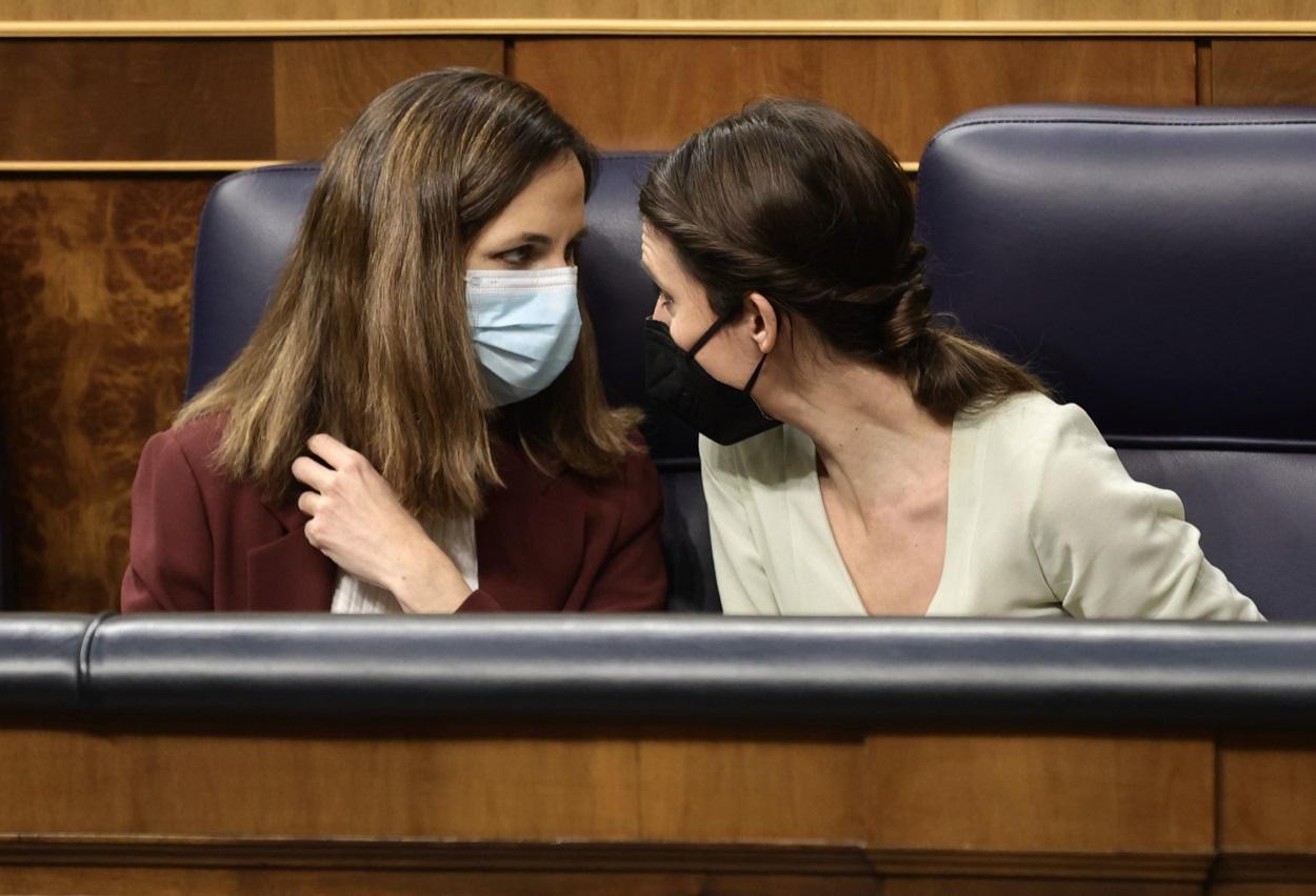 La ministra de Derechos Sociales y Agenda 2030, Ione Belarra (i), y la ministra de Igualdad, Irene Montero, conversan en una sesión plenaria en el Congreso de los Diputados