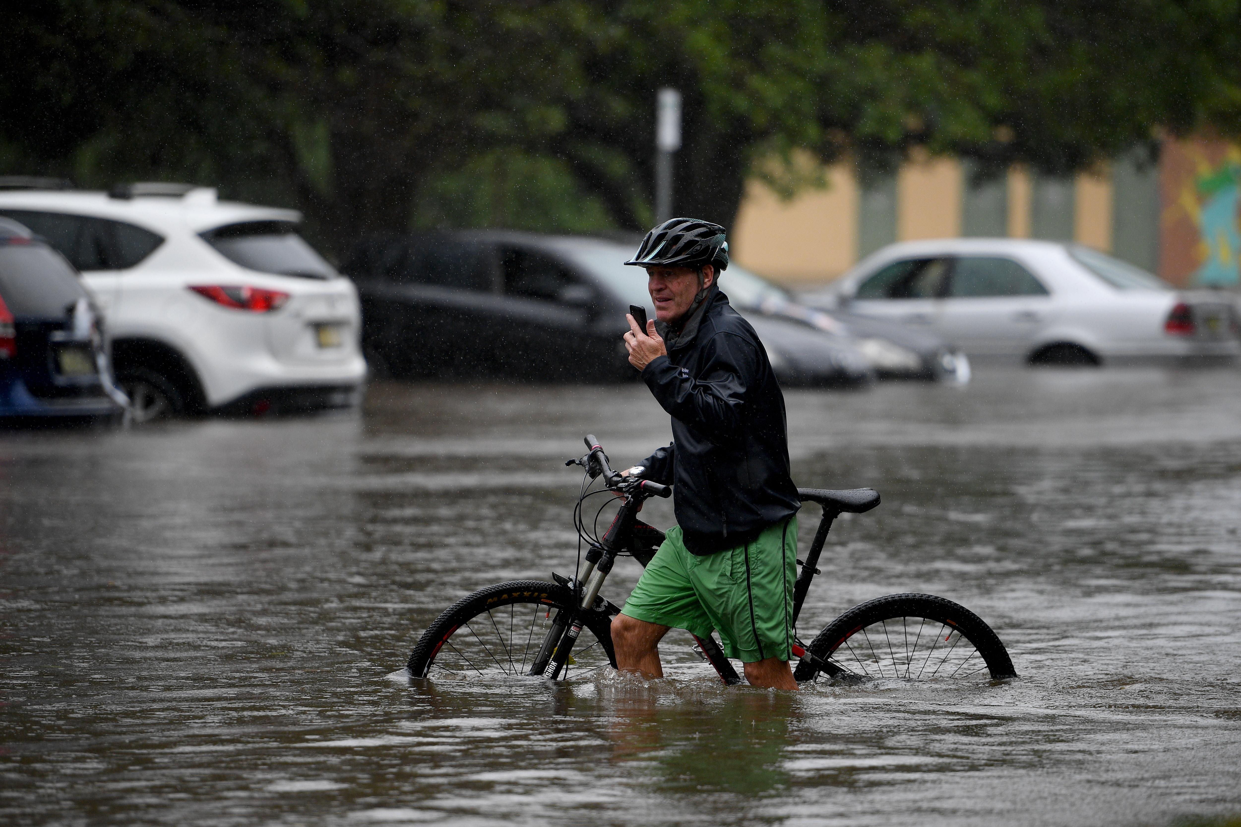 Un hombre cruza en bicicleta en mitad de una inundación en el norte de Sidney, Australia.