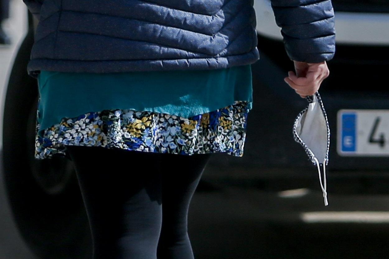 Una mujer camina con la mascarilla en la mano. Fuente: Europa Press.