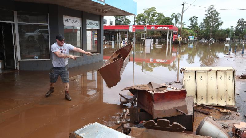 Un hombre retira escombros durante las inundaciones en el distrito financiero del centro de Lismore. Un hombre retira escombros durante las inundaciones en el distrito financiero del centro de Lismore.