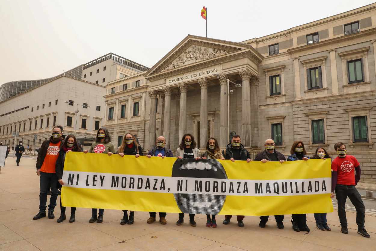 Varias personas con una pancarta en la que se lee 'Ni ley mordaza, ni mordaza maquillada', durante una protesta