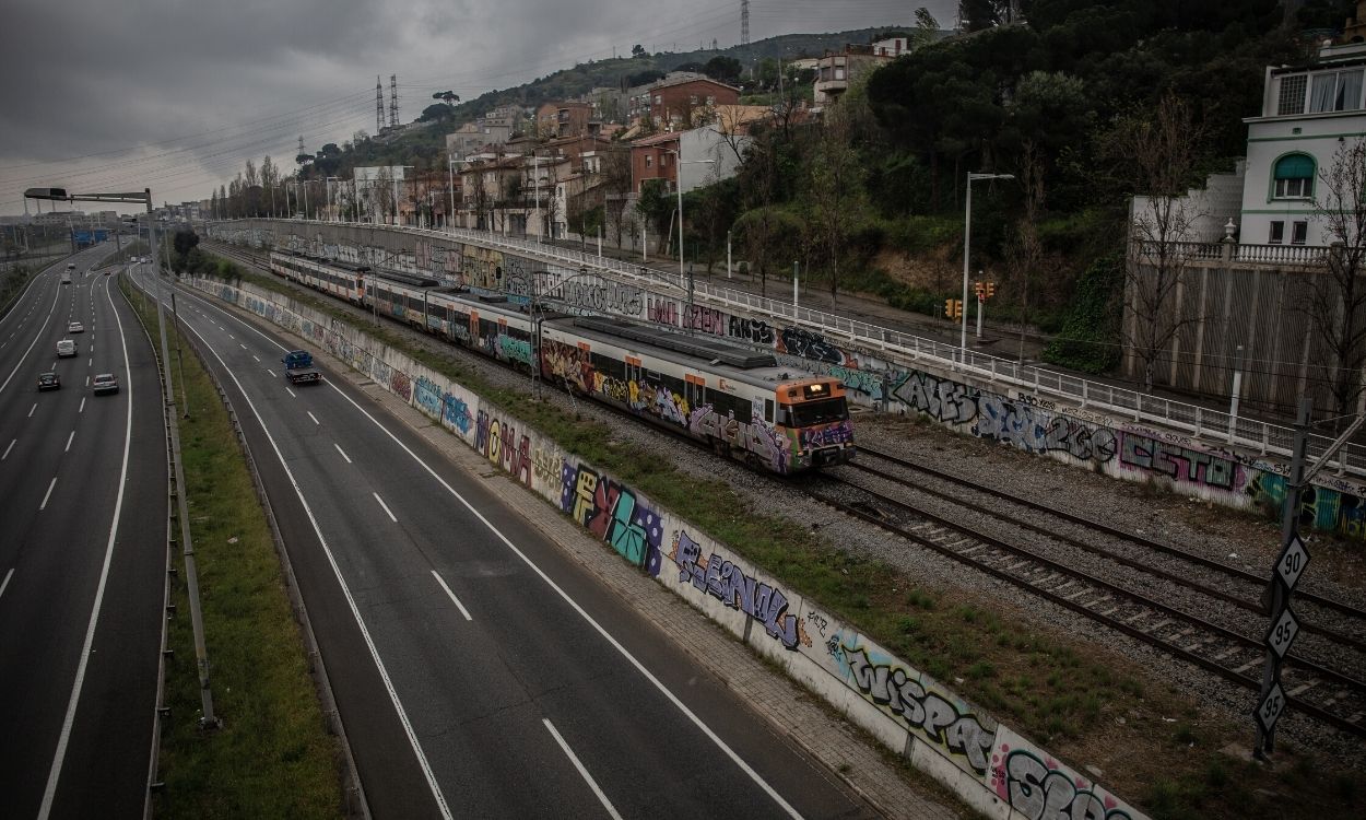 Imagen de archivo de un tren que pasando al lado de una carretera sin apenas tráfico en la entrada a Barcelona por la Autopista del Vallés