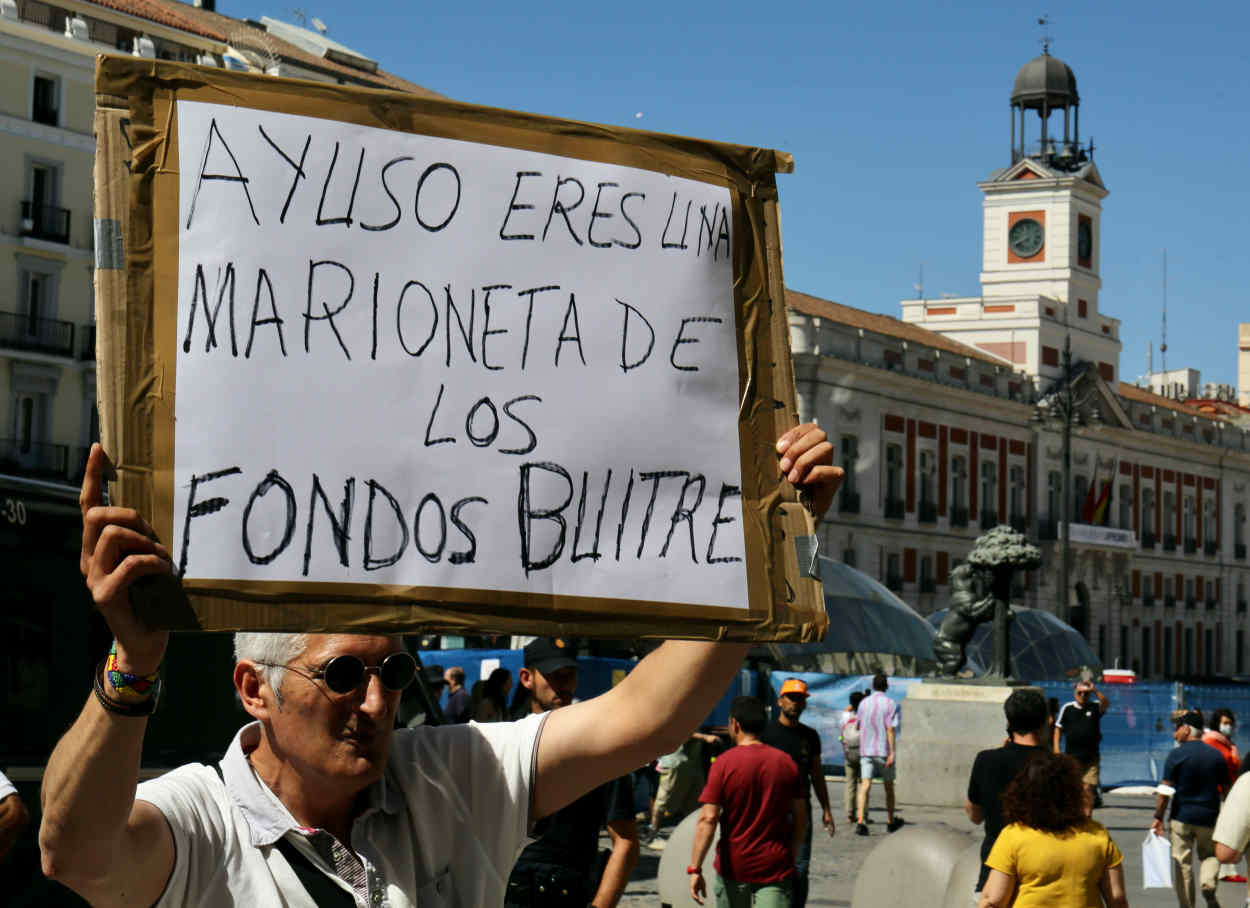 Un manifestante durante las protestas del taxi sujeta una pancarta que reza 'Ayuso, eres una marioneta de los fondos buitre'. Europa Press