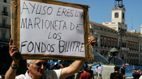 Un manifestante durante las protestas del taxi sujeta una pancarta que reza 'Ayuso, eres una marioneta de los fondos buitre'. Europa Press