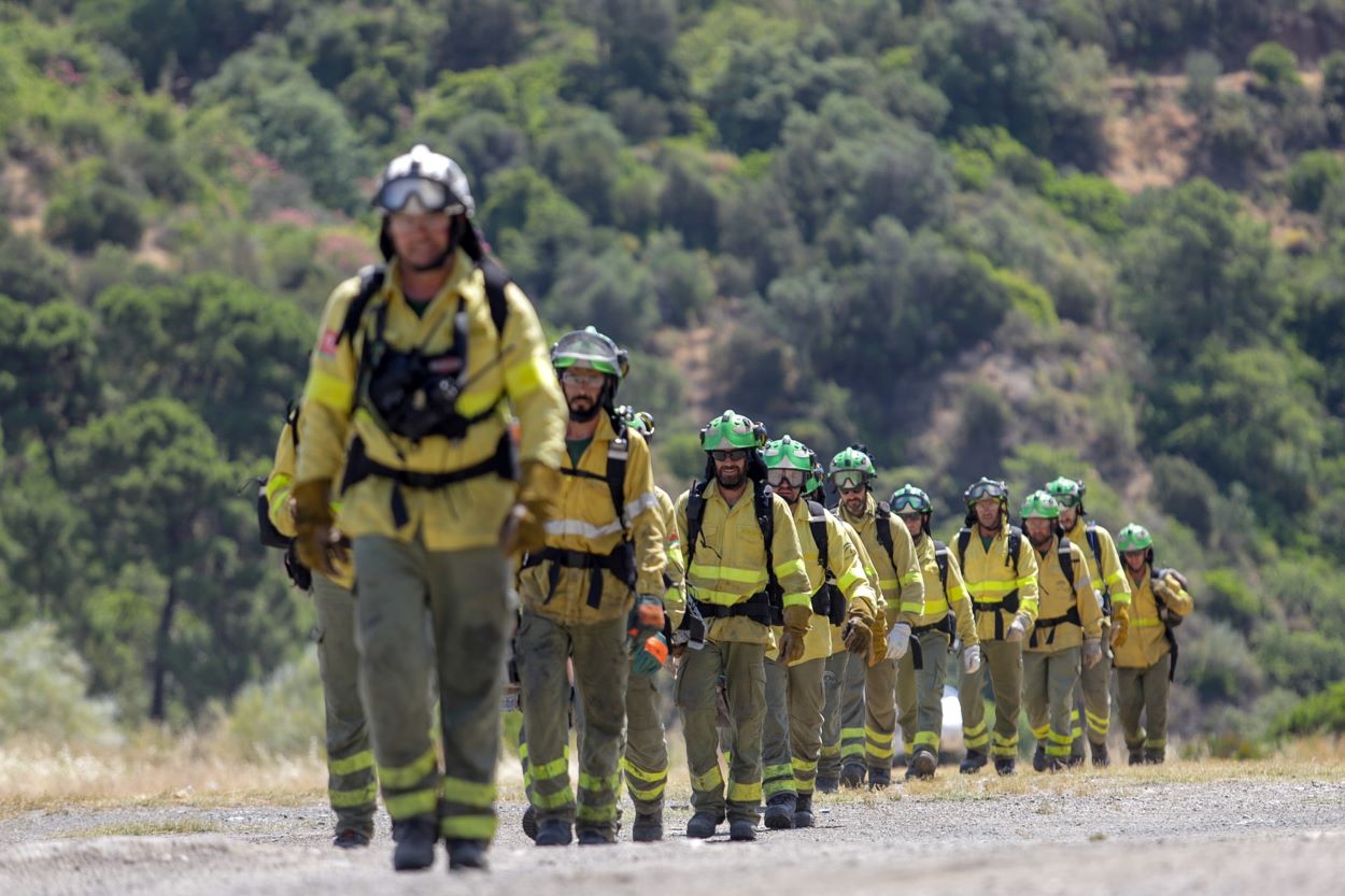 Bomberos que han estado trabajando toda la noche en el incendio forestal del Pujerra, llegan en helicóptero al puesto de mando. ÁLEX ZEA EP