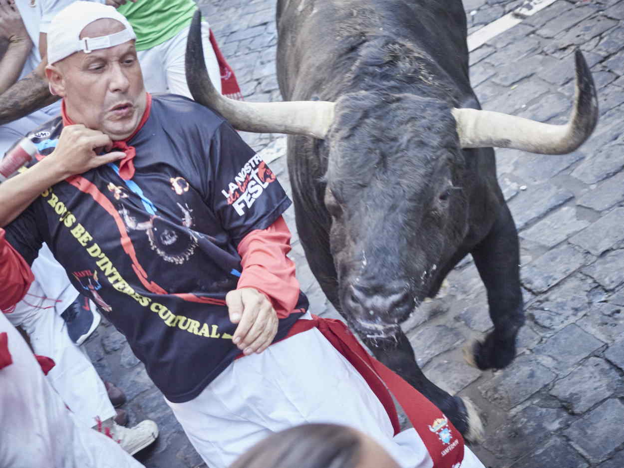 Un toro roza con sus astas a un corredor en el segundo encierro de San Fermín 2022. EP