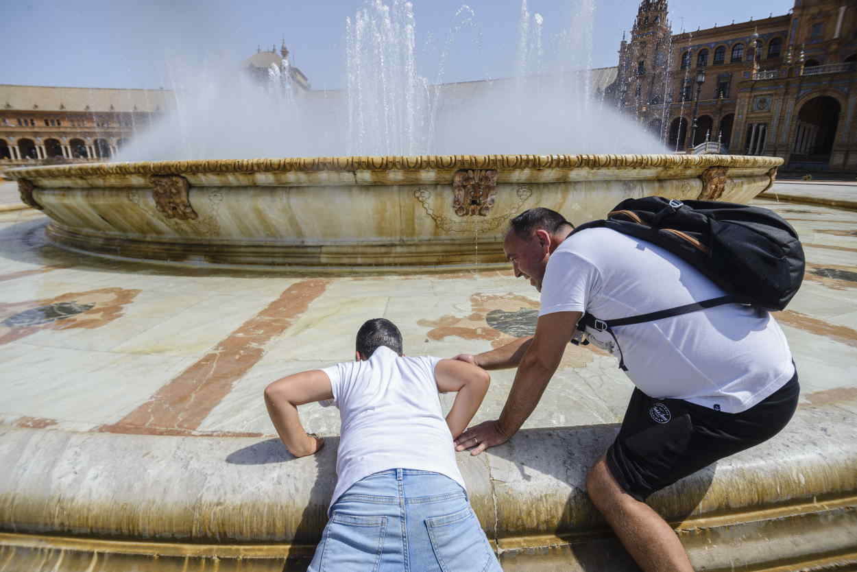 Dos personas refrescándose en una fuente debido a altas temperaturas- E.P