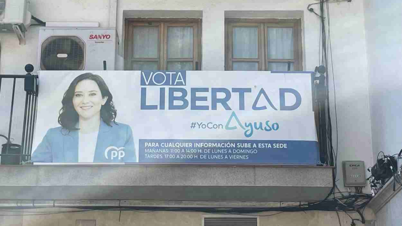 Un cartel electoral de Ayuso cuelga en la sede del PP de Torrejón de Ardoz desde 2021. PSOE
