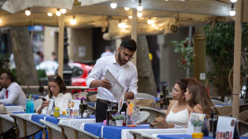 Un camarero atiende a dos clientas en la terraza. EP