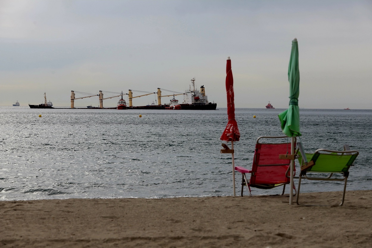 Personas en la playa observan como los equipos de salvamentos siguen evaluando y planificando el camino a seguir para extraer el combustible del buque granelero OS35. EP.