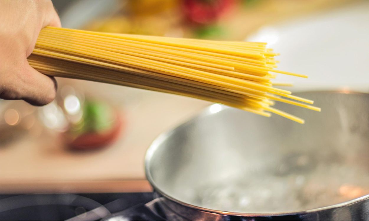 Mano echando pasta para cocer en una olla hirviendo. Pixabay