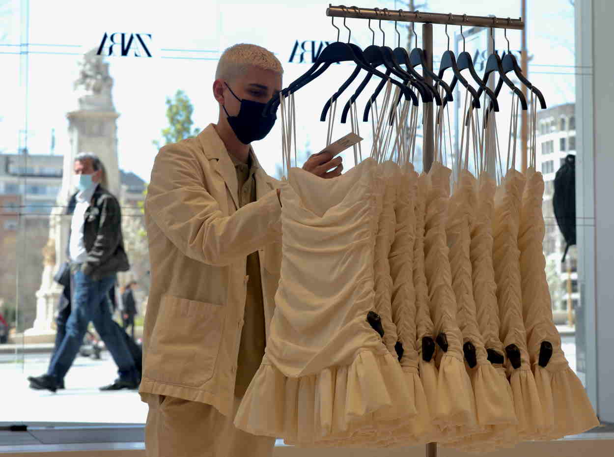 Un dependiente coloca varias prendas de ropa en una tienda de Zara. EP