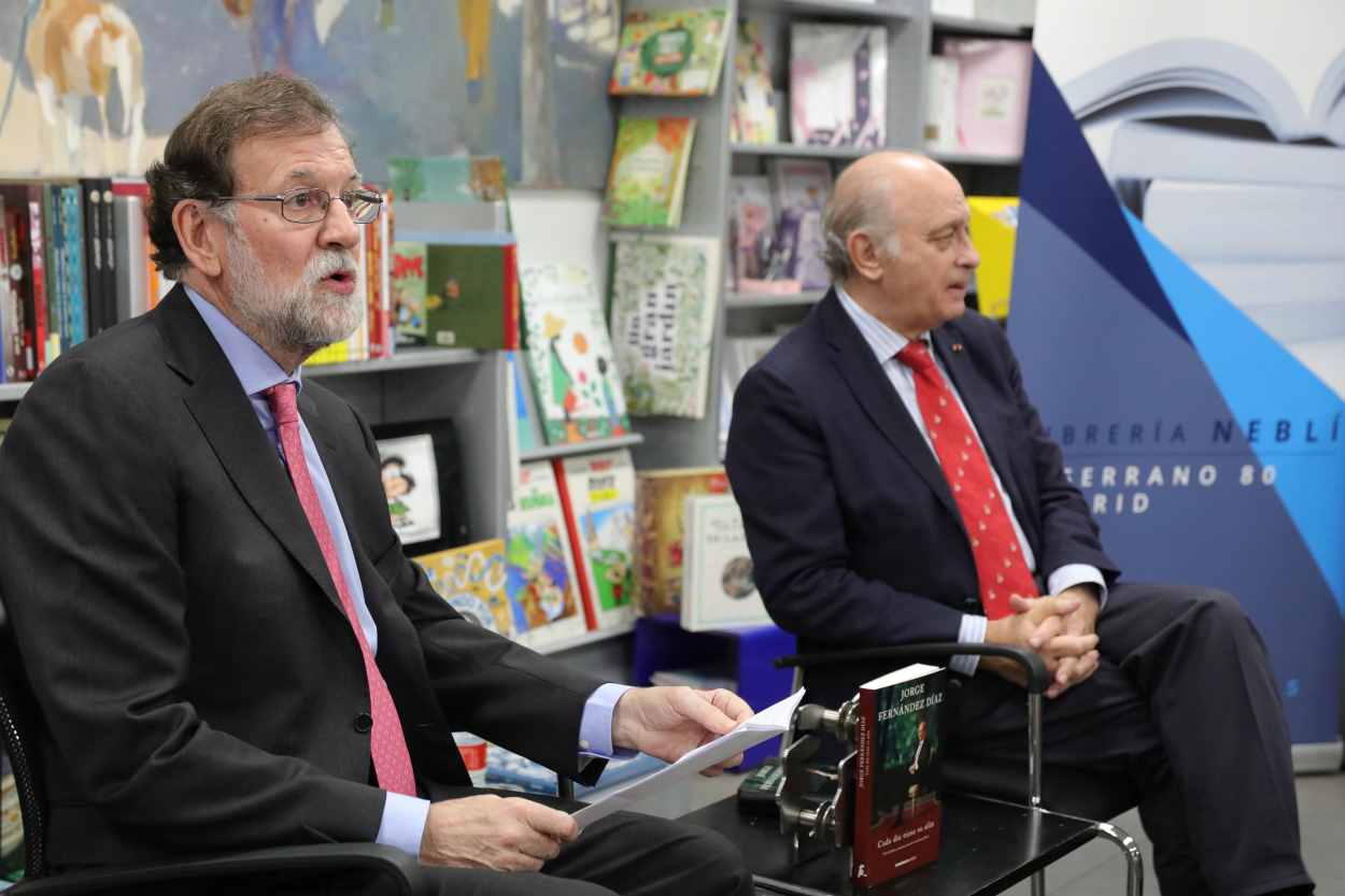 El expresidente del Gobierno Mariano Rajoy (i), y el exministro de Interior y miembro del PP, Jorge Fernández Díaz (d), durante la presentación del libro Cada día tiene su afán