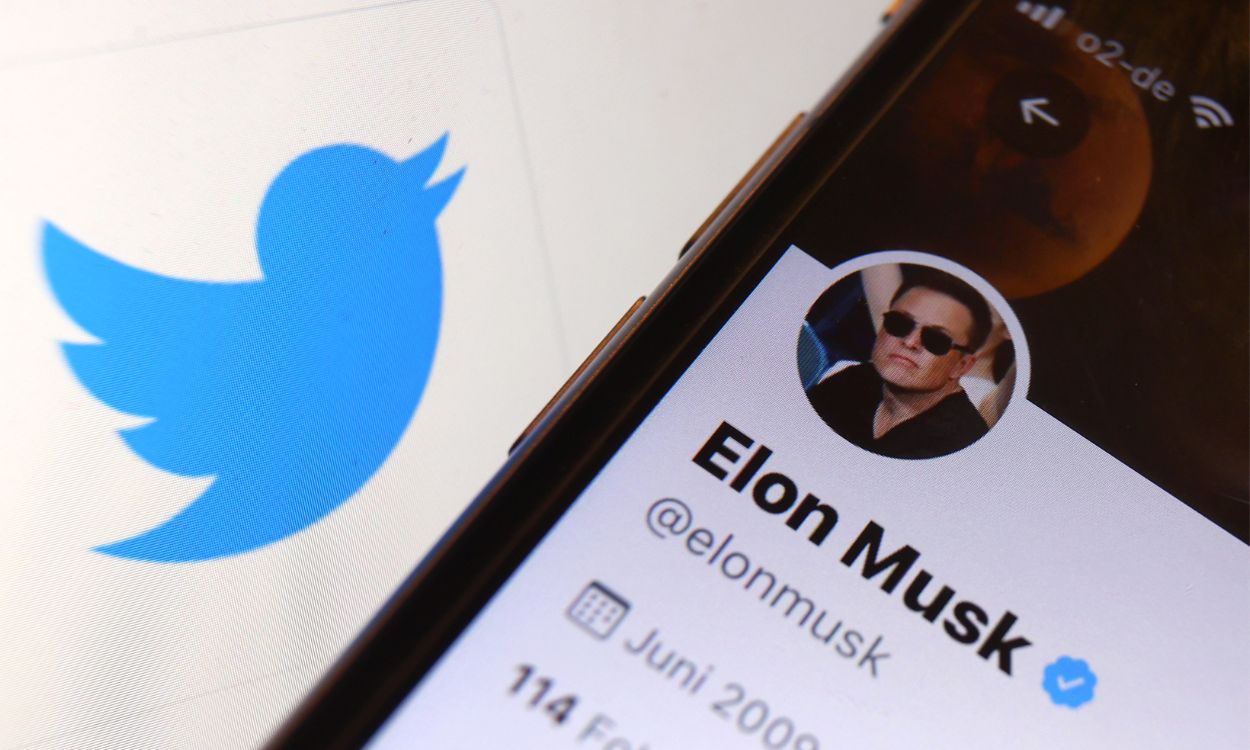 Un teléfono móvil mostrando la cuenta oficial de Twitter de Elon Musk junto al logo de la red social