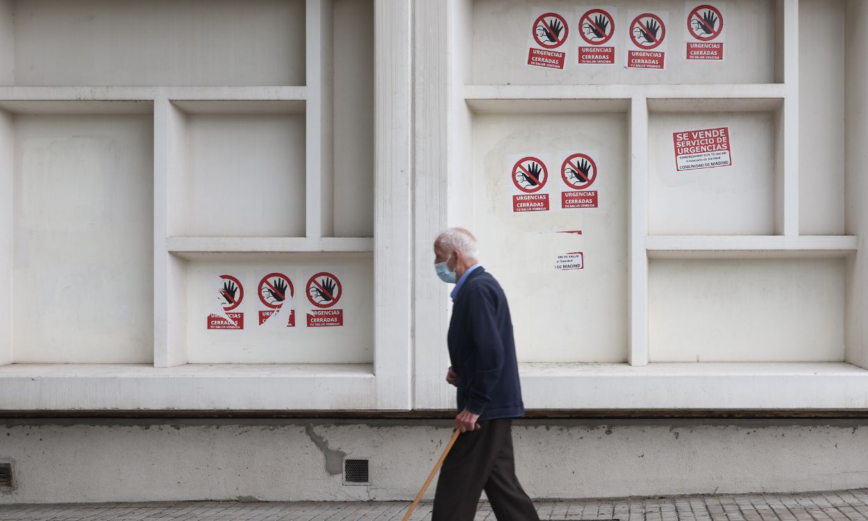 Un hombre mayor camina delante del Centro de Salud Pavones, donde se exponen carteles en contra del plan sanitario del Gobierno de Madrid. EP.