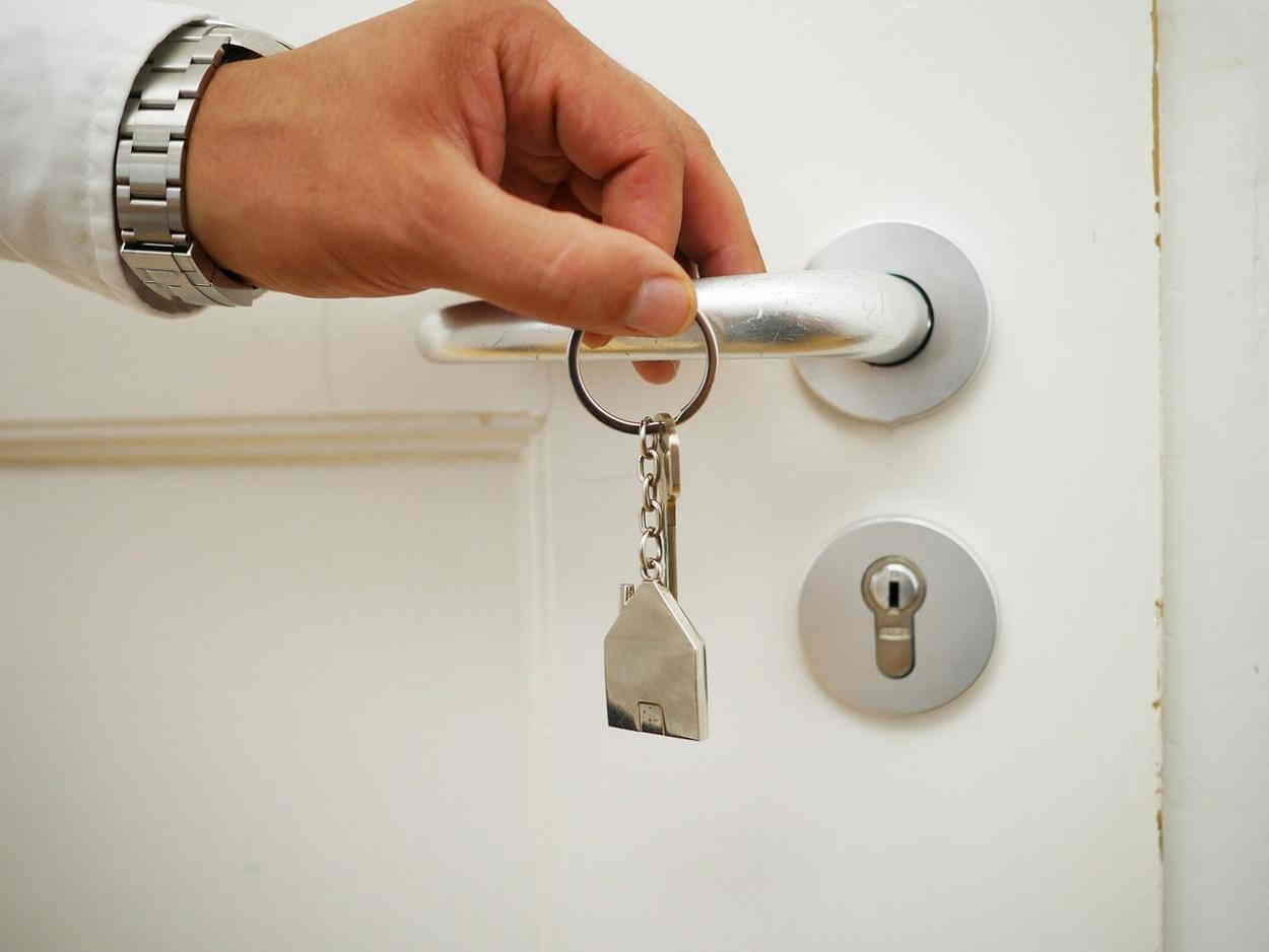 una persona abre una puerta con un manojo de llaves pixabay