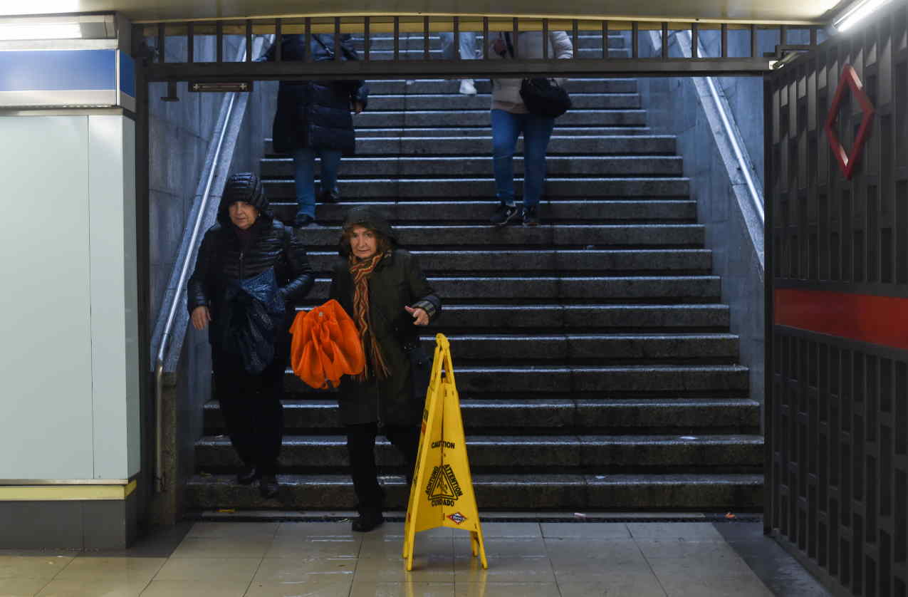 Personas entran al metro con paraguas y mojadas por la lluvia.EP