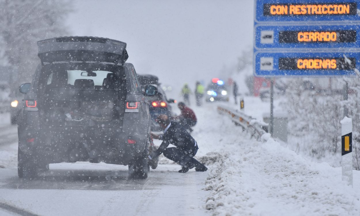 Varias personas ponen cadenas a los coches en una carretera nevada, a 16 de enero de 2023, en Huesca, Aragón (España). EP.