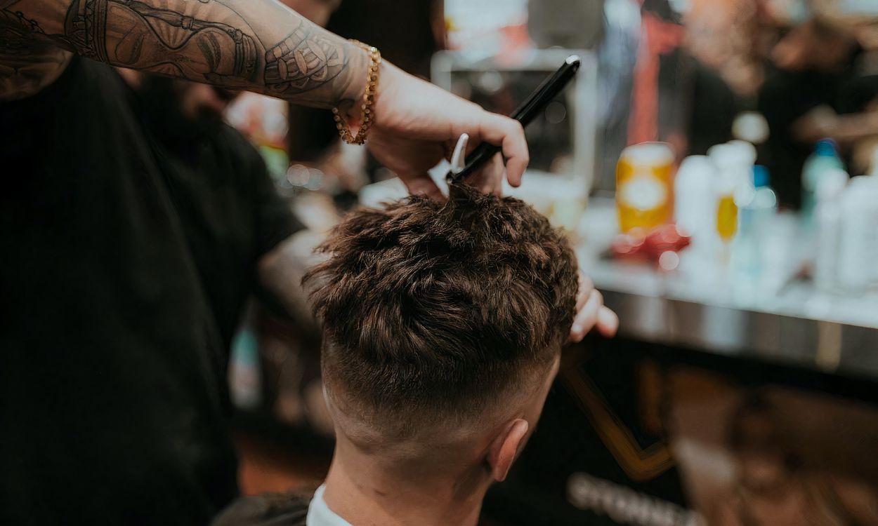 Un hombre haciéndose un corte de pelo en una peluquería. Unsplash.