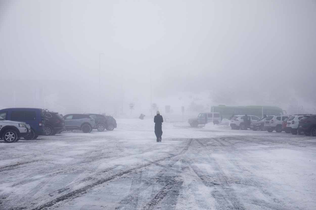 Una persona camina por la nieve en el parking del Puerto de Navacerrada, a 19 de enero de 2023, en Navacerrada, Madrid (España). Archivo