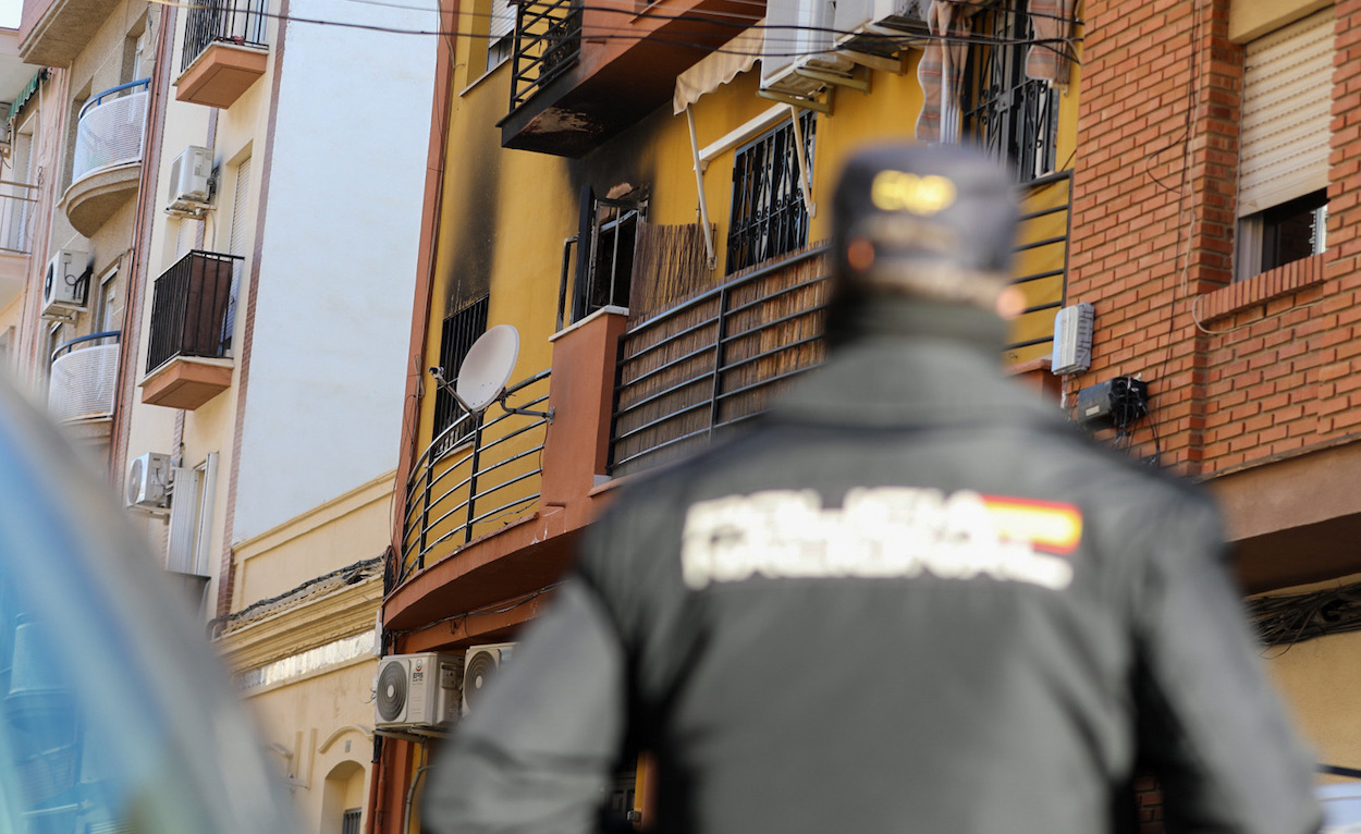 Un policía custodia el bloque en la que han fallecido tres jóvenes en el incendio de una vivienda en Huelva. A. PÉREZ/EP