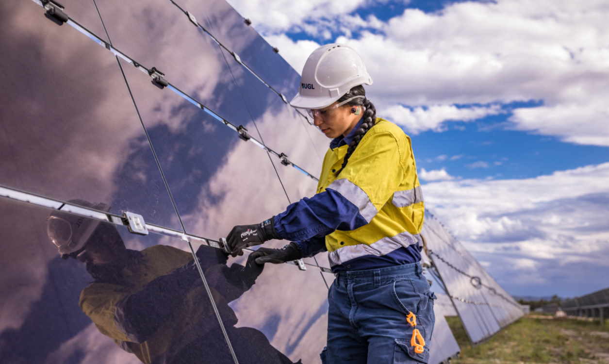 Una trabajadora de UGL coloca una placa fotovoltaica en una granja solar de Grupo ACS