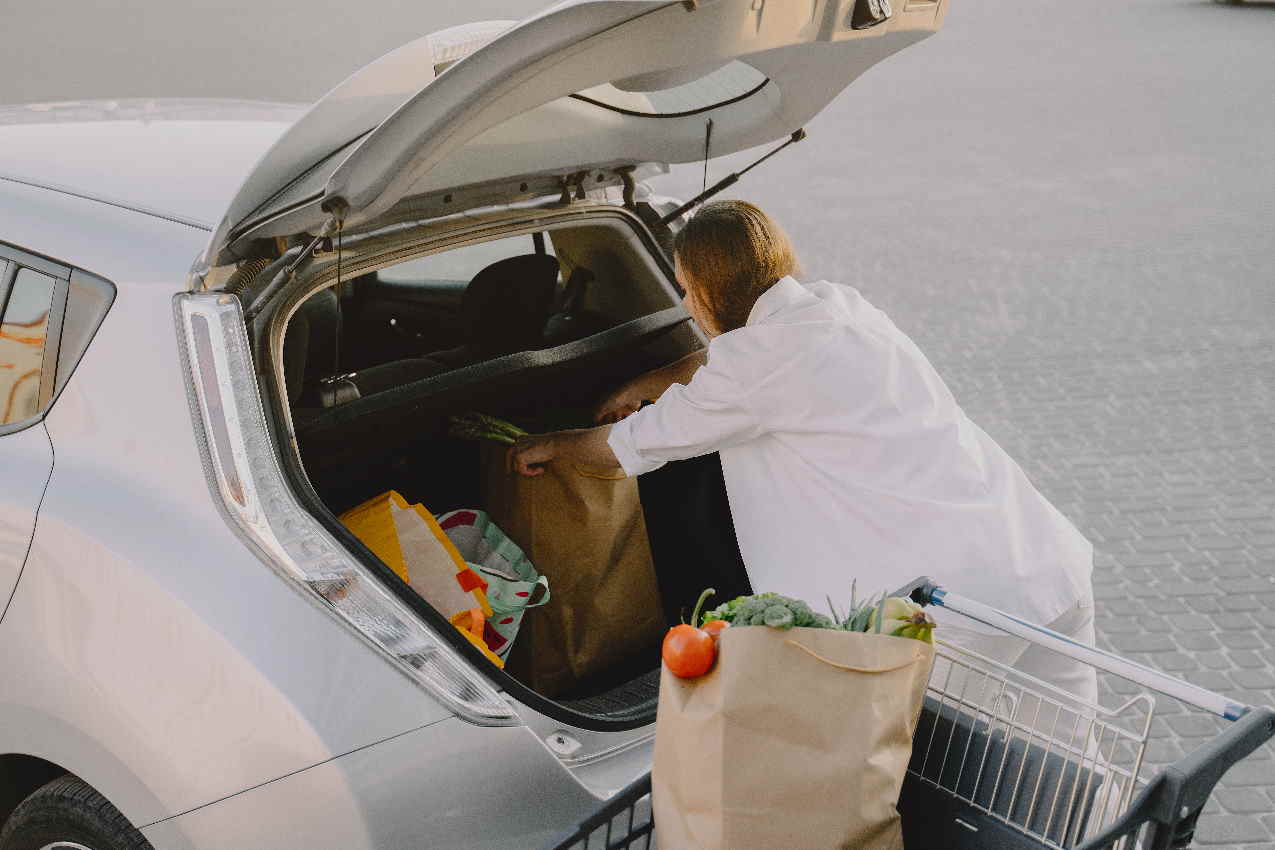 Una mujer carga productos de alimentación en un coche