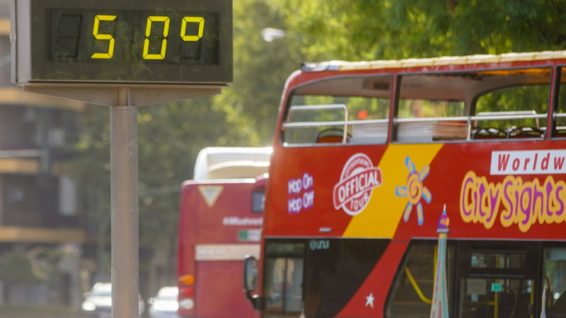 Un autobús turístico pasa sin pasajeros delante de un termómetro que marca 50ºC en julio de 2022 Sevilla. EP