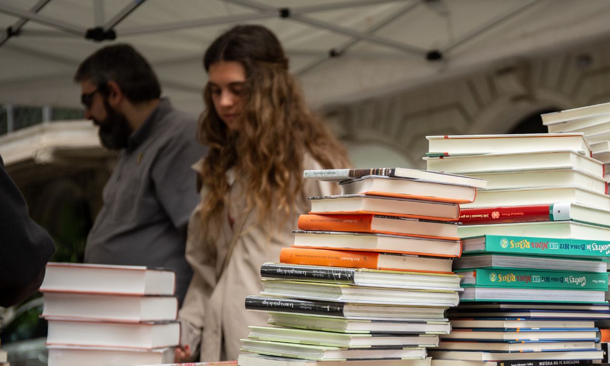 Varias personas visitan un puesto de libros en Sant Jordi 2019. EP.