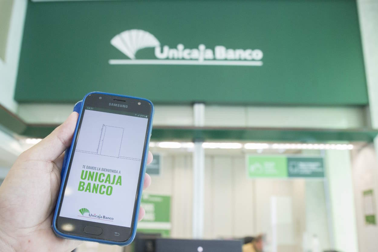 Oficina bancaria y aplicación móvil de Unicaja Banco. EP