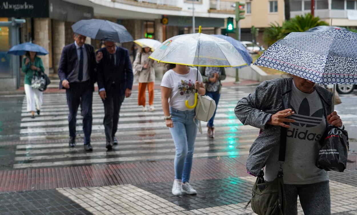 Varias personas caminando bajo la lluvia. EP