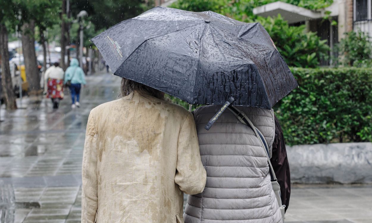 Dos personas pasean bajo la lluvia en Madrid. EP