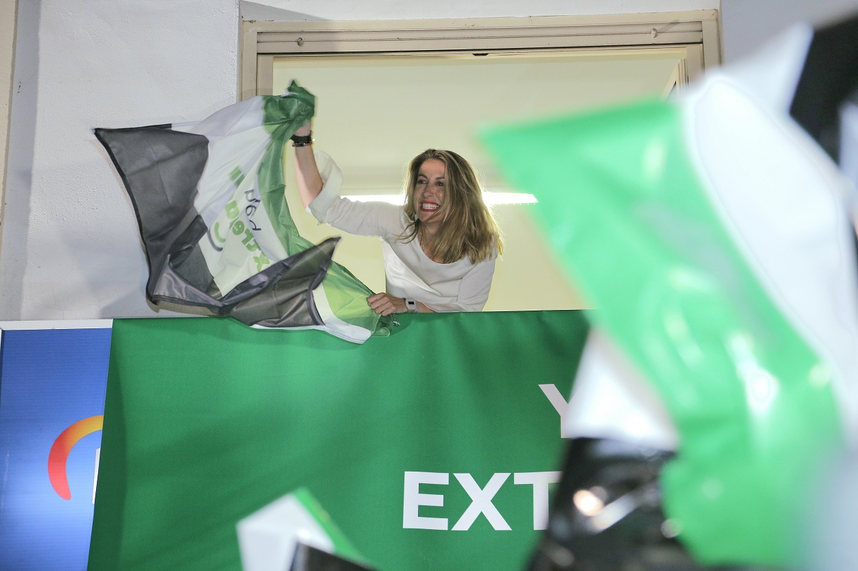 La candidata del PP a la Presidencia de la Junta de Extremadura, María Guardiola, alza una bandera a su llegada a realizar el seguimiento de la jornada electoral en la sede del PP de Mérida. EP.