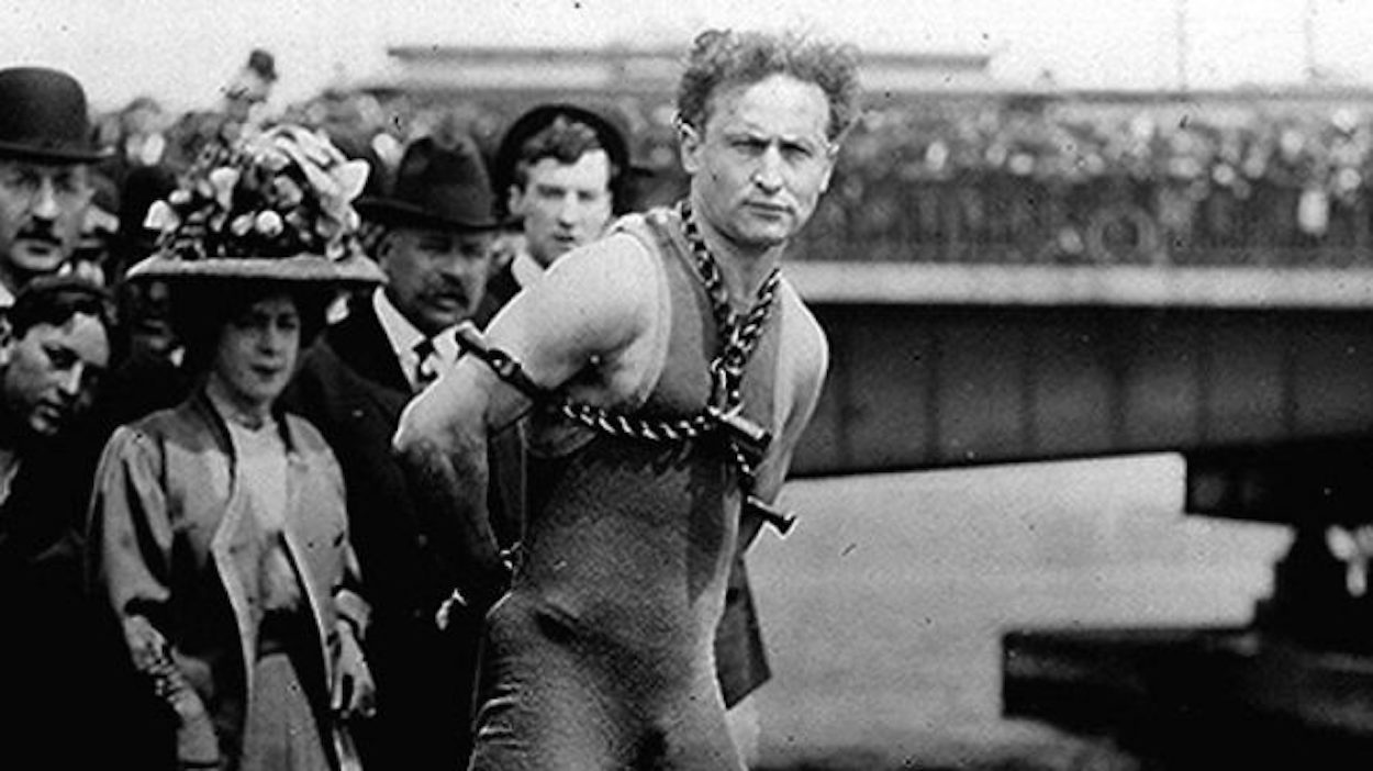 El mago Harry Houdini, encadenado durante uno de sus célebre números de escapismo.