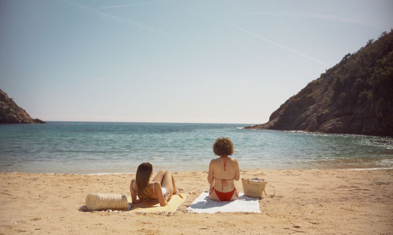 Dos personas expuestas al sol en una playa. 