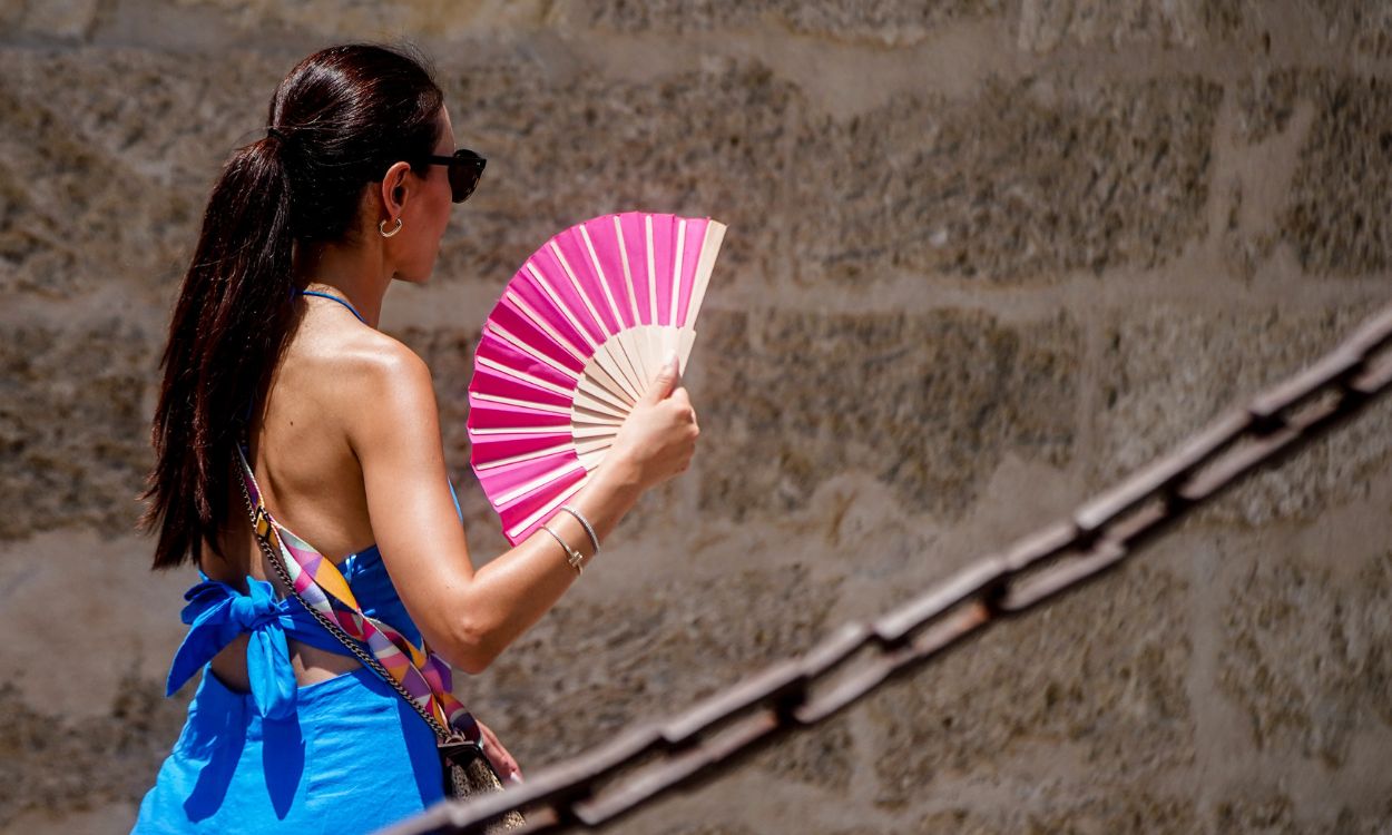 Una turista camina por Sevilla abanicándose debido a las altas temperaturas. EP