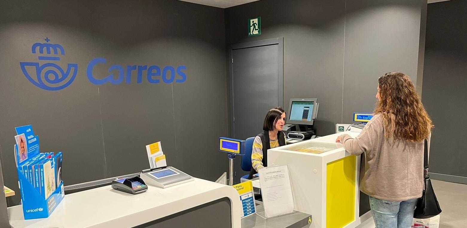 Imagen de una mujer siendo atendida en una oficina de correos.