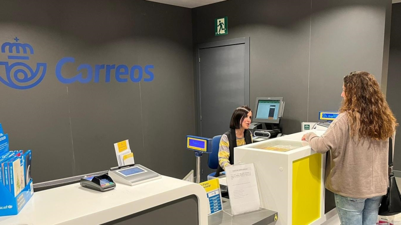 Imagen de una mujer siendo atendida en una oficina de correos.