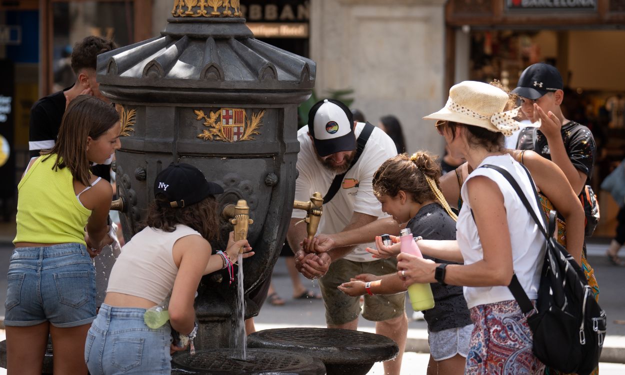 Varias personas se refrescan en una fuente pública por las altas temperaturas. EP.