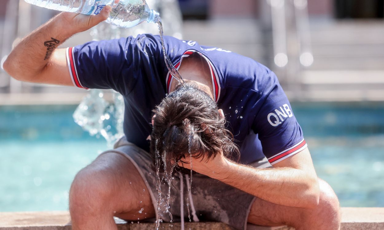 Un joven se tira una botella de agua por encima para combatir una ola de calor en Madrid. EP
