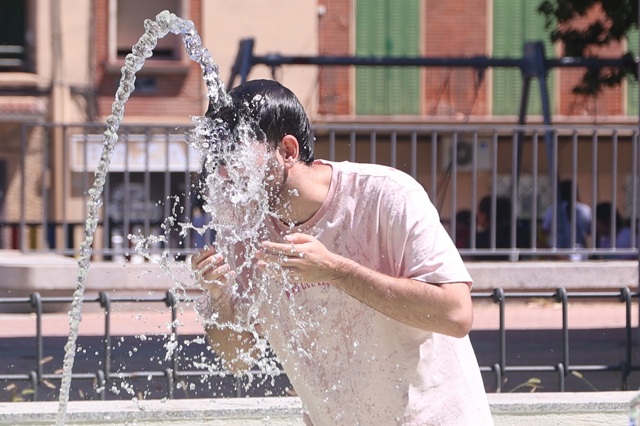 Una persona se refresca en una fuente, a 7 de agosto de 2023, en Madrid (España). EP.
